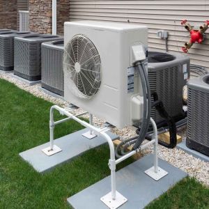 Outdoor heat pump and air conditioner units installed beside a home on mounting pads for residential HVAC systems