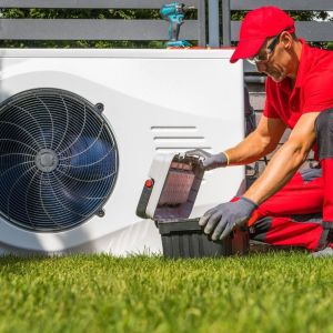 HVAC technician performing maintenance on an outdoor heat pump unit in a residential yard