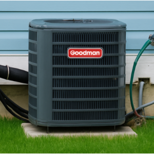 Goodman outdoor air‑conditioning condenser next to a light blue vinyl‑sided house on a green lawn