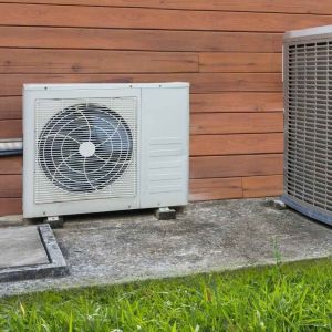 Goodman heat pump condenser and air conditioner side by side outside a home.
