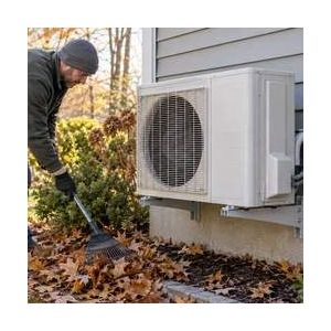 Homeowner clearing leaves near an outdoor mini-split heat pump
