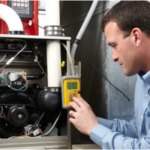 HVAC technician inspecting and testing a furnace with diagnostic tool during maintenance