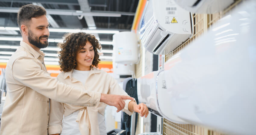 Smiling couple shopping for a new air conditioner and comparing mini split units in a home appliance store