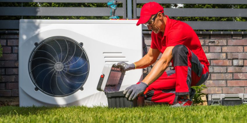 Professional Heat Pump Maintenance by HVAC Technician HVAC technician performing maintenance on an outdoor heat pump unit in a residential yard