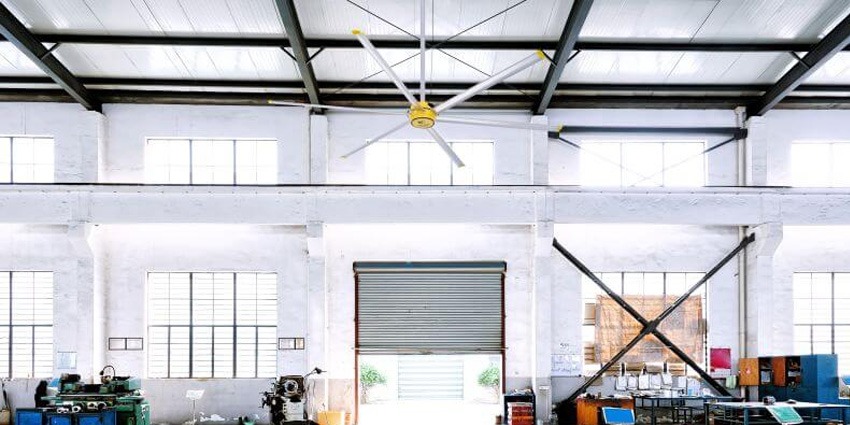 Industrial warehouse interior featuring a large HVLS ceiling fan mounted near the ceiling to improve airflow and air circulation across the workspace.