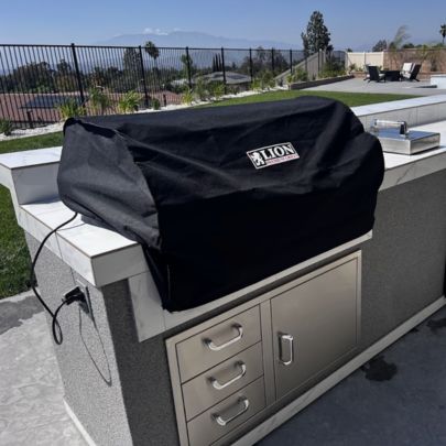 Built-in gas grill covered with weather-resistant grill cover in outdoor kitchen