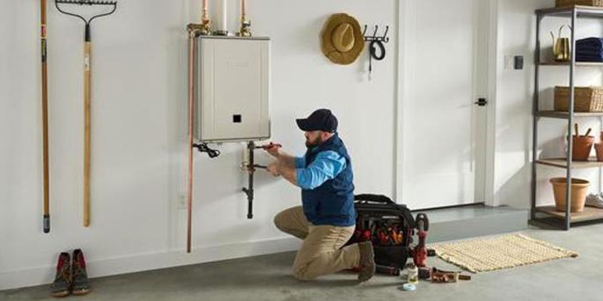 Technician installing a Noritz EZ Series Pro tankless water heater in a residential garage