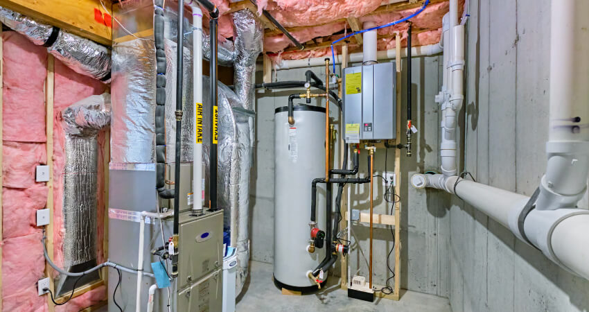 Central air and furnace replacement system in a residential basement — learn real installation and replacement costs at HVACDirect.com Residential furnace, water heater, and central air conditioning system installed in a finished basement — example of a complete HVAC setup for home comfort and efficiency